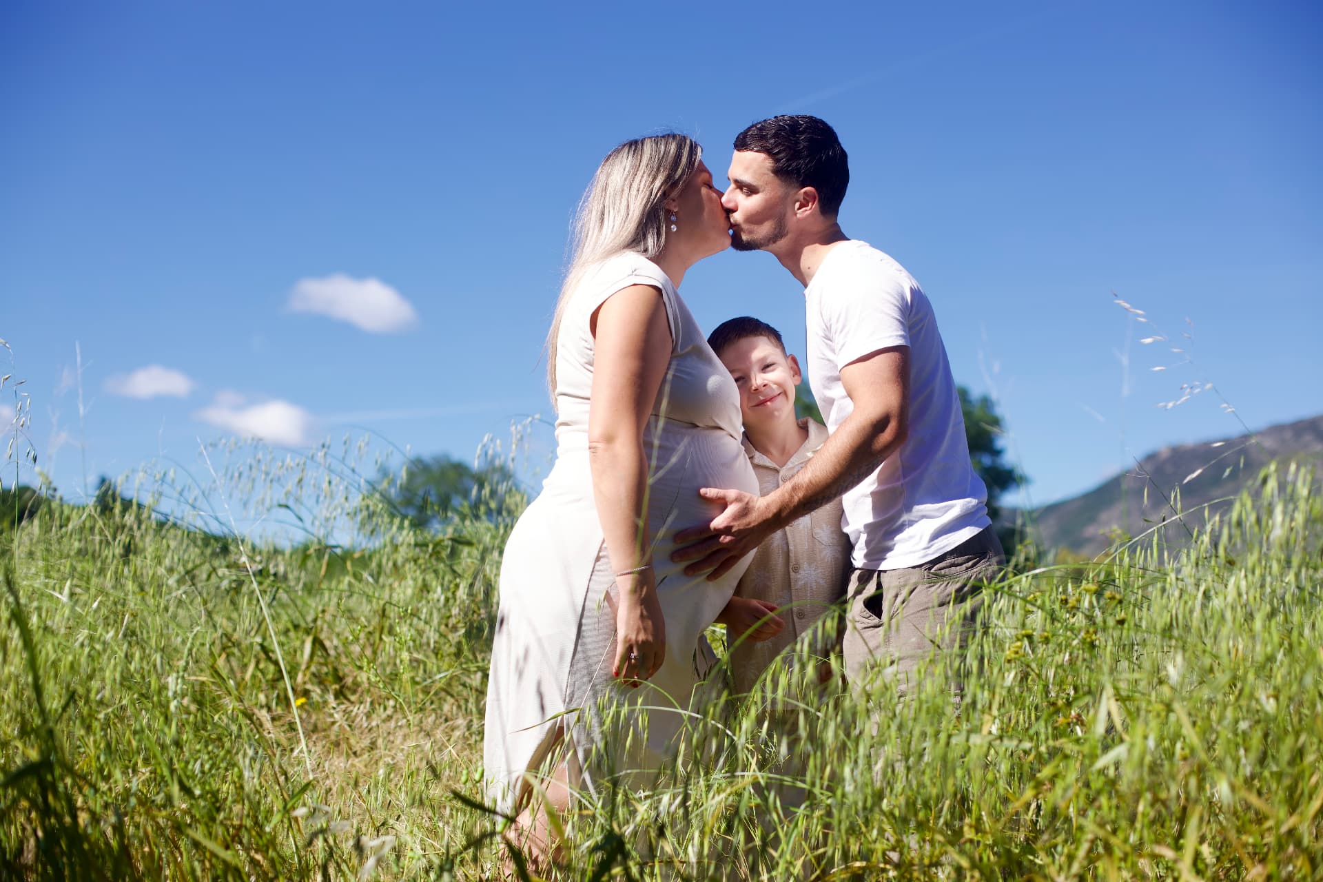 Couple s'embrassant dans un champ avec leur fils