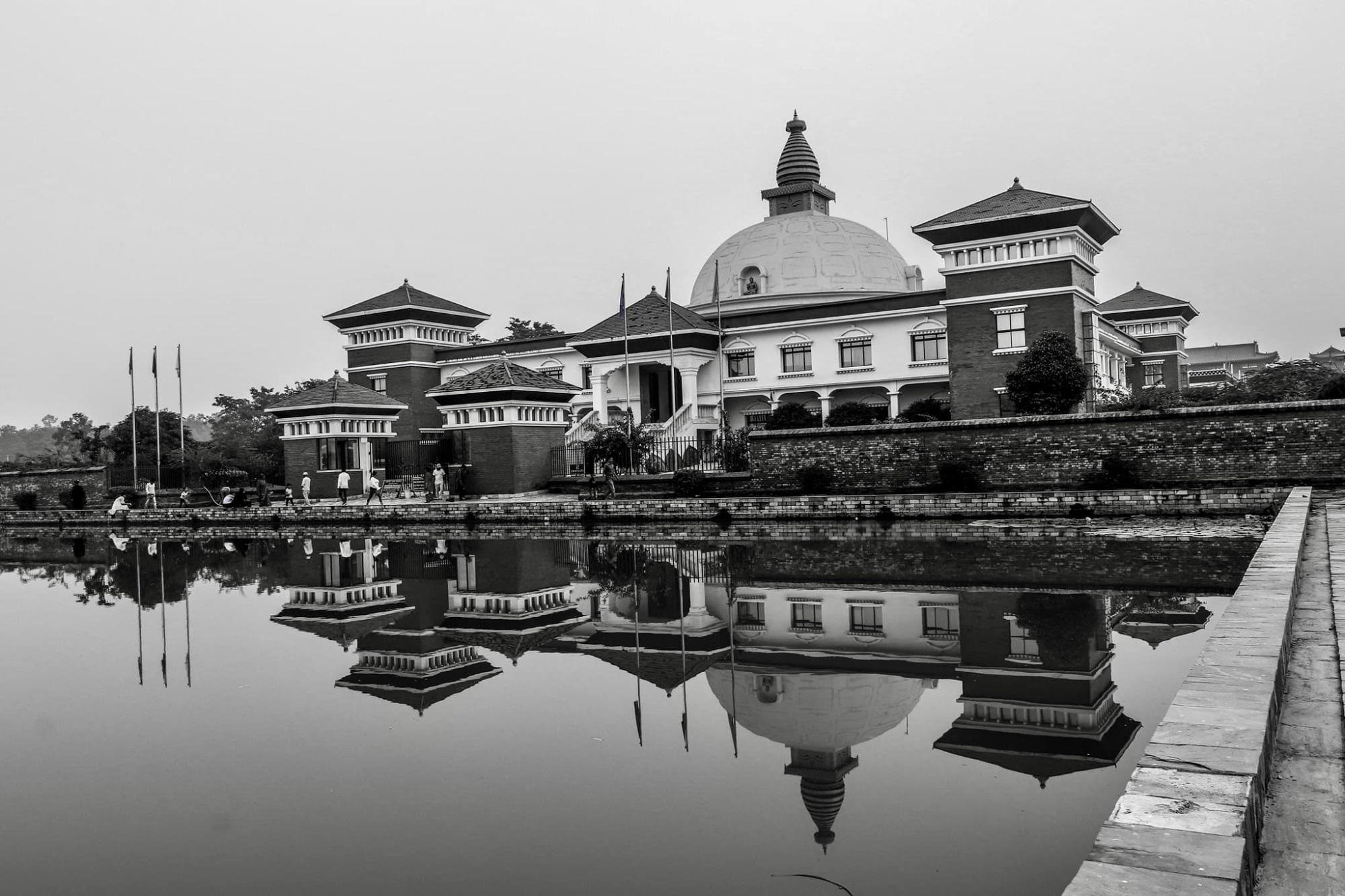 Photographie en noir et blanc d'un temple avec un grand dôme se reflétant dans un bassin d'eau.