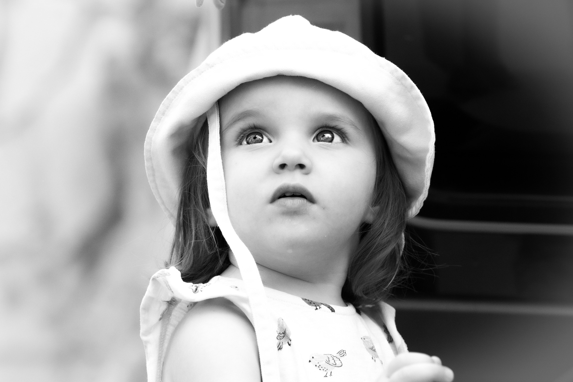 Portrait en gros plan et en noir et blanc d'un jeune enfant portant un chapeau et regardant vers le haut.